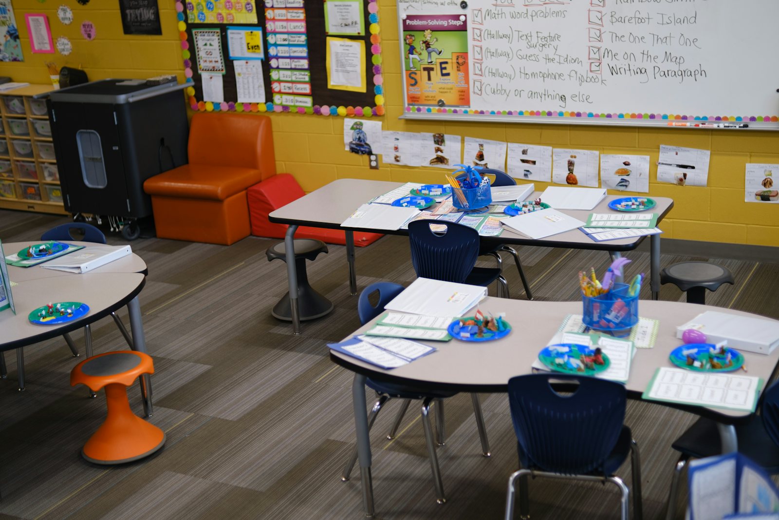 A bright classroom with blue chairs around low tables, ready for the first day